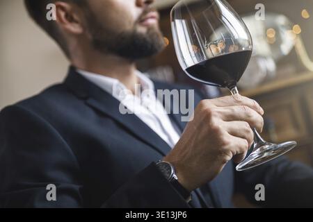 Mann in schwarzem Anzug mit einem Glas Rotwein Stockfoto