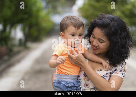 Porträt einer glücklichen asiatischen Mutter und eines multiethnischen Baby-Sohnes, die sich im Freien zusammenschließen Stockfoto