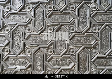 Detaillierte Nahaufnahme eines kunstvollen islamischen geometrischen Musters, das auf eine historische Metalltür geschnitzt wurde. Traditionelle arabeske Motive und kalligraphische Dekorationen Stockfoto