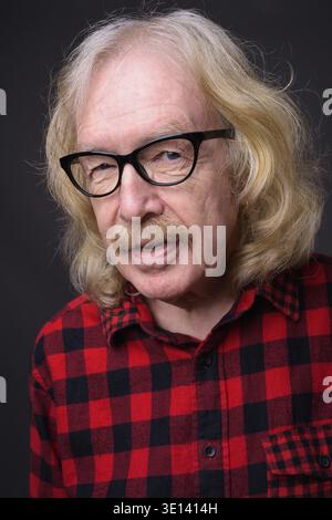 Studio shot der älteren Mann mit Schnurrbart tragen rot kariertem Hemd gegen grauer Hintergrund Stockfoto