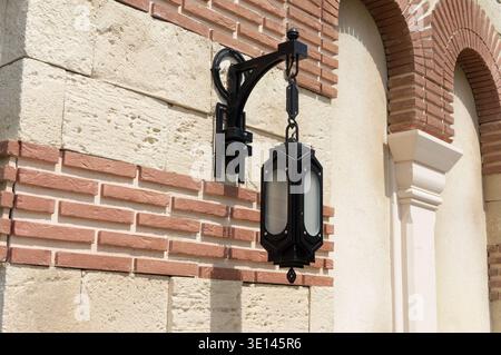 Eine Lampe, die an einer Wand hängt. Die Lampe ist schwarz-weiß. Die Wand ist aus Ziegeln Stockfoto