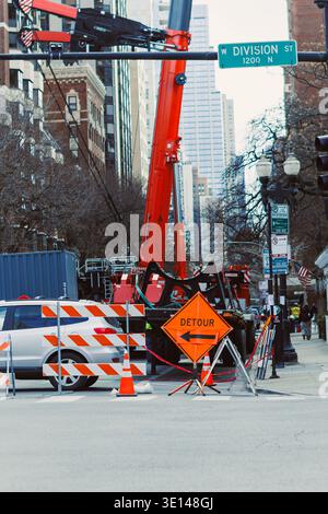 Bauarbeiter richteten Ausrüstung in der Division Street mit Warnschildern auf einen Umweg. Fahrzeuge fahren während der Arbeit vorbei. Bäume lin Stockfoto