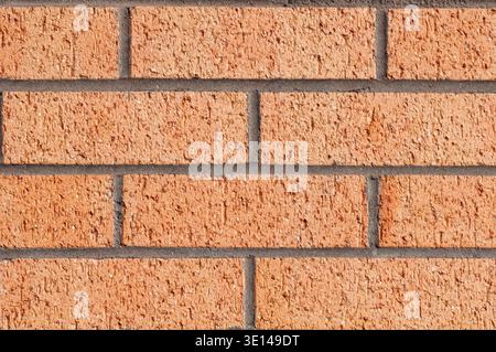 Saubere orangefarbene Ziegelwand mit gleichmäßigem Muster und sichtbaren Mörtellinien Stockfoto