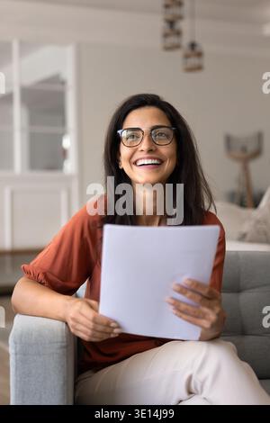 Glückliche Frau, die positive Nachrichten in Dokumenten liest Stockfoto