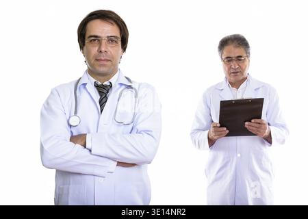Jungen persischen Mann Arzt mit verschränkten Armen und Senior persischen Mann Doktor Lesung über Zwischenablage Stockfoto
