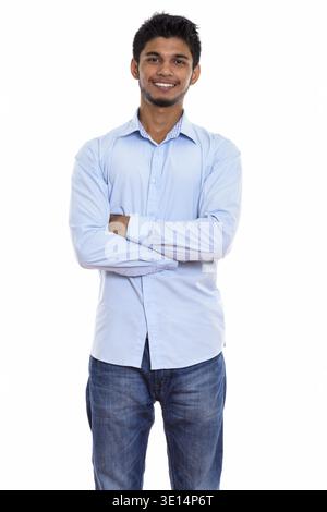 Studio shot junger indischer Mann glücklich lächelnd und stand mit verschränkten Armen Stockfoto