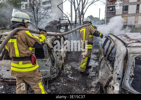 Feuerwehrleute löschen brennendes Auto mit Wasserschlauch Stockfoto