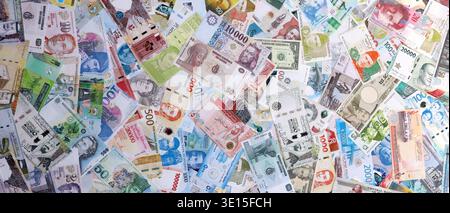 Viele Banknoten aus verschiedenen Ländern der Welt mit unterschiedlichen Stückelungen. Große Mengen an Geldscheinen in verschiedenen Währungen. Währungsumtausch-Konzept Stockfoto