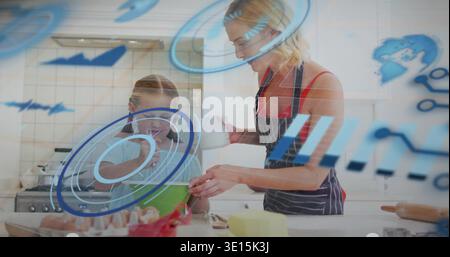 Mutter in gestreifter Schürze, während Mädchen an der Haustheke mit Glaskanne rührt, HUD-Überzüge Stockfoto