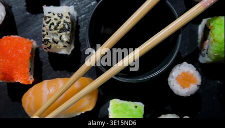 Sushi-Teller mit verschiedenen Sushi-Sorten und Essstäbchen über einer kleinen Schüssel Sojasauce Stockfoto