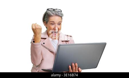 Seniorin feiert Erfolg und zeigt Leistung auf dem Laptop an Stockfoto