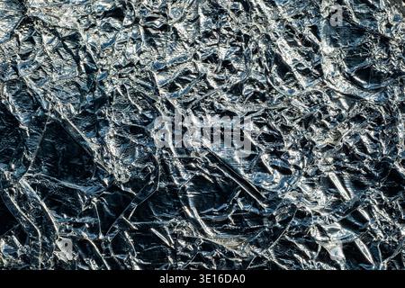 Zerknitterte Oberfläche aus glänzender Aluminiumfolie, die einen metallischen abstrakten Texturhintergrund erzeugt Stockfoto
