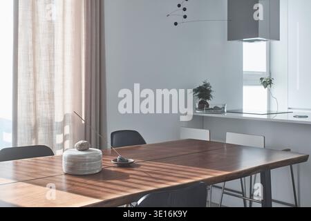 Esstisch aus Holz neben einer offenen weißen Küche. Stockfoto