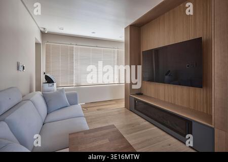Minimales Wohnzimmer mit eingebauter Medienwand und weichem Tageslicht. Stockfoto