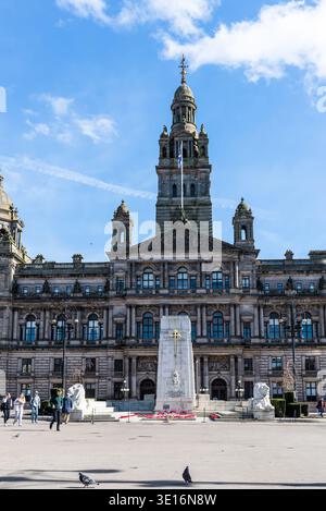 Glasgow, Schottland, Großbritannien - 24. März 2025: Die großen Glasgow City Chambers erhebt sich über dem George Square, eingerahmt von Statuen, einem Kriegsdenkmal und Fußgängern Stockfoto