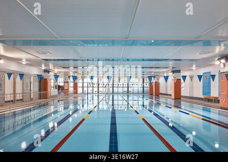 Hallenschwimmhalle mit Gassen, Terrasse und heller Deckenbeleuchtung. Stockfoto
