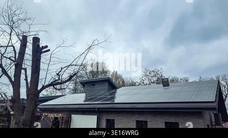Ein modernes Gebäude mit Solarpaneelen auf dem Dach. Ein umweltfreundliches Energiesystem auf dem Dach eines Gebäudes in einem Stadtpark. Einbau der Verkleidung. Stockfoto