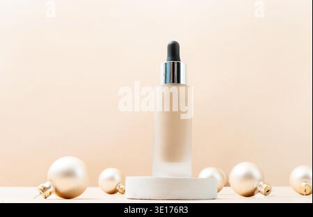 Eine minimalistische Szene mit einer Grundierflasche auf dem Podium mit dekorativen weihnachtskugeln auf beigem Hintergrund. Showcase mit einer Bühne für Produkte, Modell-Design, saisonabhängig Stockfoto