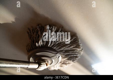 Schmutziger Moppkopf, der bei der Innenreinigung von der Decke hängt, Nahaufnahme mit Schattendetails Stockfoto
