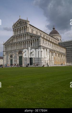 Kathedrale von Pisa, Dom von Pisa. Ikonisches romanisches Meisterwerk in Pisa, Italien. Besucher in der Nähe der Fassade mit dunklen Wolken darüber. Stockfoto