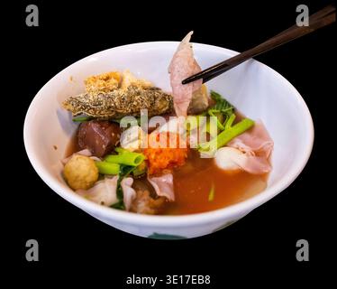 Gestanzte Yentafo Pink Meeresfrüchte flache Nudeln mit Fisch Fleischbällchen auf schwarz isoliert. Stockfoto