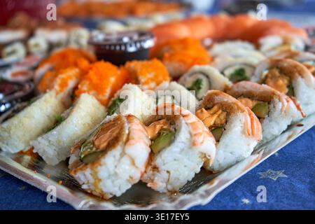 Ein Nahaufnahme einer aufwendigen Sushi-Platte mit verschiedenen Arten japanischer Brötchen, die auf einem rechteckigen Servierteller angeordnet sind. Im Stockfoto