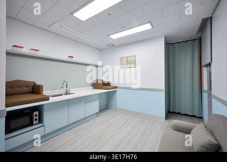 Kompakte Lounge mit Kochnische, Sofa und pastellfarbener Einrichtung. Stockfoto