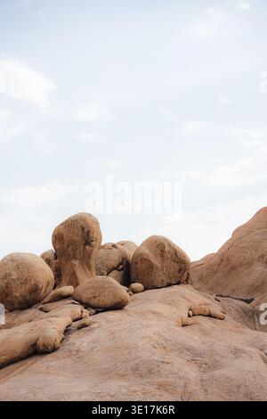 Große runde Felsbrocken ruhen unter einem hellblauen Himmel in der atemberaubenden Landschaft von Spitzkoppe, Namibia. Diese natürliche Felsformation ist ein beliebtes Reiseziel Stockfoto