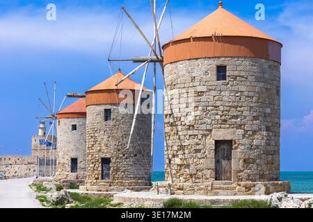 Die historischen Windmühlen des Hafens von Mandraki in Rhodos, Griechenland, säumen den Hafen mit Yachten, die in der Nähe verankert sind, und bieten einen malerischen Blick auf die Stockfoto
