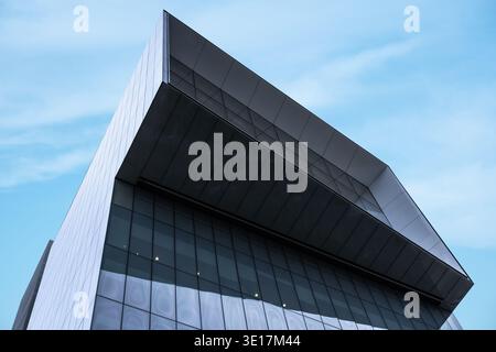 Ein moderner Büroturm mit schlankem architektonischem Design, klaren Linien und großen Glasfenstern, überragt vor dem Hintergrund einer vibra Stockfoto