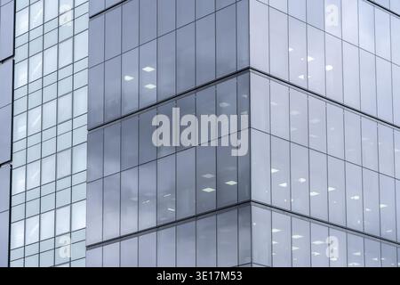 Aus nächster Nähe sehen Sie die Fassade eines modernen Firmengebäudes mit eleganten Glaspaneelen und reflektierenden Oberflächen. Das architektonische Design hebt Finan hervor Stockfoto