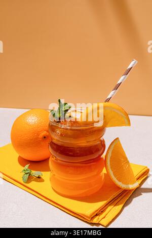 Ein erfrischendes Americano mit geeisten Zitrusfrüchten mit einer leuchtenden Orangenscheibe, serviert in einem stilvollen Glas mit Strohhalm. Begleitet von frischen Orangen, perfekt Stockfoto