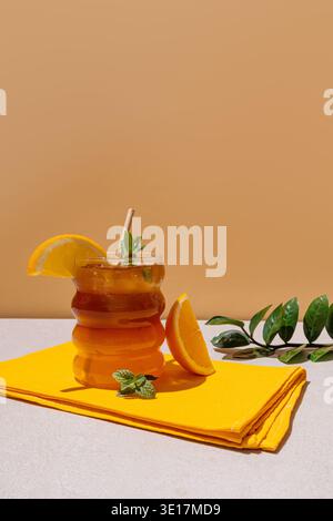 Ein erfrischendes Americano mit eisgekühlten Zitrusfrüchten wird elegant in einem Glas mit einer leuchtenden Orangenscheibe auf einer kräftigen gelben Serviette serviert. Perfekt für einen Stockfoto