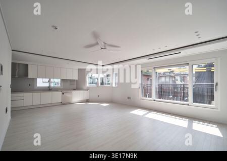 Wohnzimmer mit Sonnenlicht und weißen Wänden und breiten Fenstern. Stockfoto