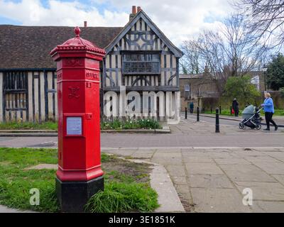 Ein seltener viktorianischer Penfold-Säulenkasten steht an der Church Lane in Walthamstow Village, London, im März 2026. Dieser ikonische sechseckige Briefkasten, der von dem Architekten John Wornham Penfold entworfen und zwischen 1866 und 1879 hergestellt wurde, ist einer von nur wenigen originalen „Penfolds“, die in der Hauptstadt noch in Gebrauch sind. Die Box verfügt über eine unverwechselbare Kappe mit Akanthusblättern, einer Knospe und dekorativen Kugeln. Im Hintergrund befindet sich das Ancient House, ein denkmalgeschütztes Fachwerkhaus aus dem Jahr 1435, was es zu einem der ältesten erhaltenen Wohngebäude Londons macht Stockfoto