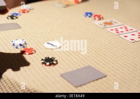 Poker Chips und Spielkarten verstreut auf strukturierten Tisch mit Dealer Button während Casino Kartenspiel, Inlandsspiel Stockfoto