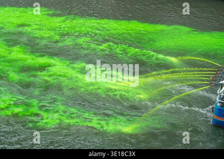 Schläuche, die gelben und grünen Farbstoff in den Fluss gießen, Wasser grün machen, Umweltverschmutzungskonzept, Umweltproblem, Wasserverschmutzung Stockfoto