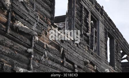 Verkohlte Holzwand eines durch Feuer zerstörten Gebäudes, rustikale Ruinen Stockfoto