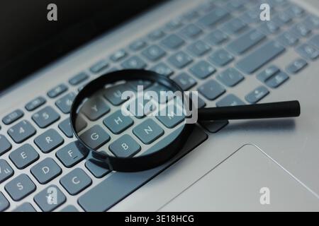 Lupe auf der Laptop-Tastatur. Stockfoto
