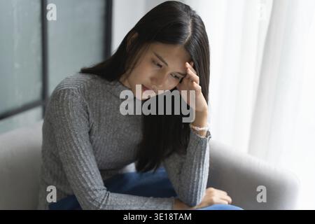 Junge asiatische Frau fühlt sich einsam traurig krank gestresst auf Sofa zu Hause allein für Healthcare Wellness Lifestyle Stockfoto