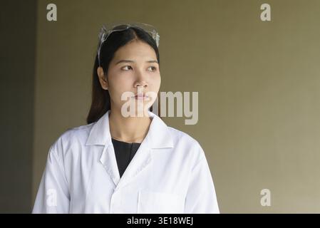 Junge asiatische Wissenschaftlerin mit Labormantel und Schutzbrille Stockfoto