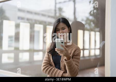 Junge asiatische Frau, die ihr Smartphone für Geschäftskommunikation im Freien in Urban City nutzt Stockfoto