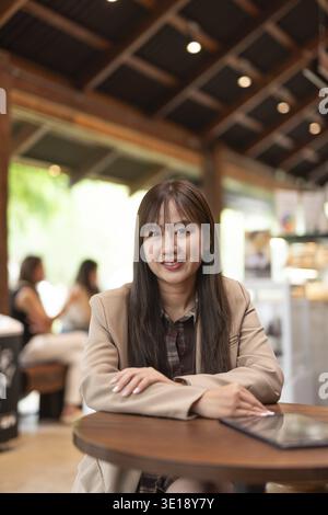 Junge asiatische Frau im Café lächelnd und sitzend Stockfoto
