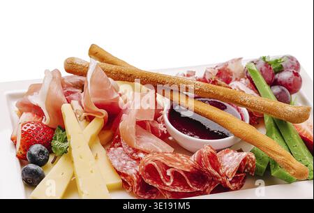 Auf einer wunderschön angeordneten Platte gibt es eine Vielzahl von Wurstwaren, Käse, frischem Obst und Dip-Sauce. Dieser appetitliche Aufstrich ist perfekt für Gat Stockfoto