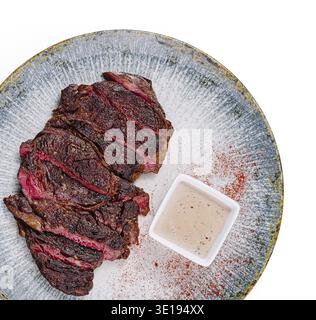 In Scheiben geschnittenes gegrilltes Rindersteak mit Gewürzen und Sauce auf dem Teller serviert Stockfoto