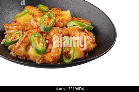 Süß-saure Garnelen mit Reis, Ananas und Chili auf schwarzem Teller Stockfoto