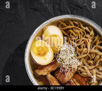 Blick von oben auf eine köstliche Ramen-Nudelschüssel mit saftigen Schweinefleisch-Scheiben, Eiern und Sprossen Stockfoto