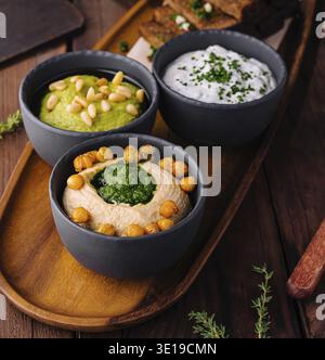 Appetitliche Auswahl an Bier-Snacks mit Toast und verschiedenen Dips auf einer rustikalen hölzernen Servierplatte Stockfoto