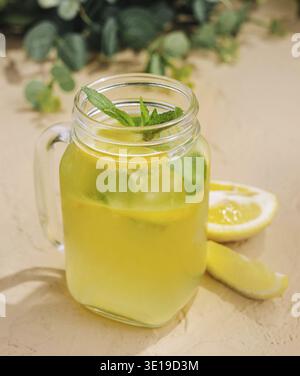 Erfrischende hausgemachte Limonade mit Minz- und Zitronenscheiben wird in einem Glas aus maurerglas auf einem Tisch serviert Stockfoto