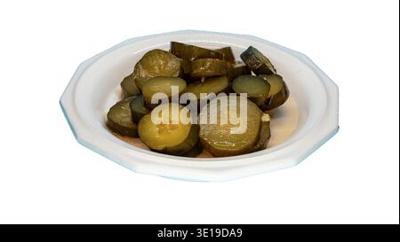 Geschnittene Gurken werden ordentlich auf eine weiße Platte gelegt. Die Einrichtung ist eine Küche mit Tageslicht. Die Gurken variieren in Dicke und Farbe und zeigen die Details des Gemüses an. Stockfoto